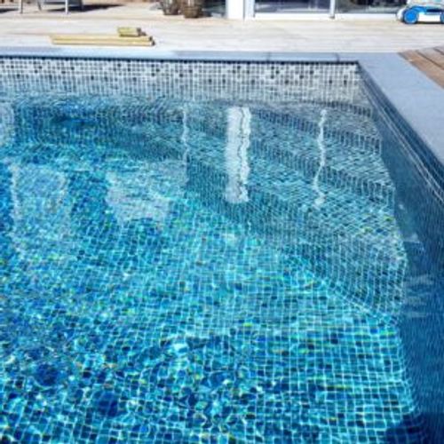 Pool med ljus mosaikliner, trappa längs gaveln och grå sarg