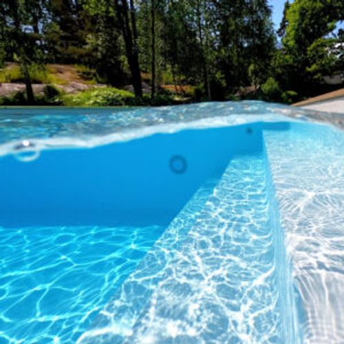 Pool med turkos liner och trappa i skogsmiljö